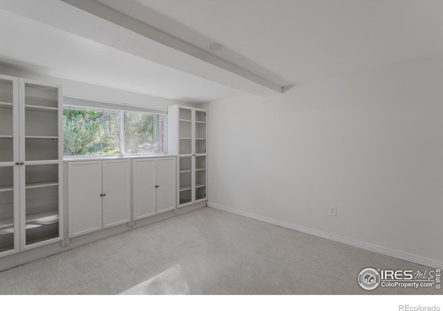 empty room with light colored carpet and beamed ceiling