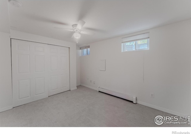 unfurnished bedroom with a baseboard heating unit, light colored carpet, ceiling fan, and a closet