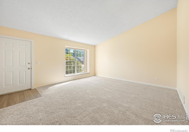 unfurnished room featuring a textured ceiling and carpet