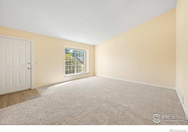 177 S Polk Ave, Louisville, CO 80027 - unfurnished living room featuring baseboards, carpet flooring, lofted ceiling, and a textured ceiling