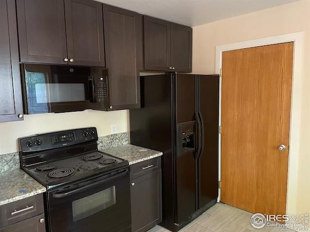 kitchen with light stone counters, dark brown cabinets, and black appliances