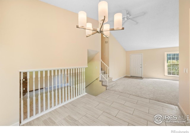 empty room with ceiling fan with notable chandelier, light colored carpet, and high vaulted ceiling