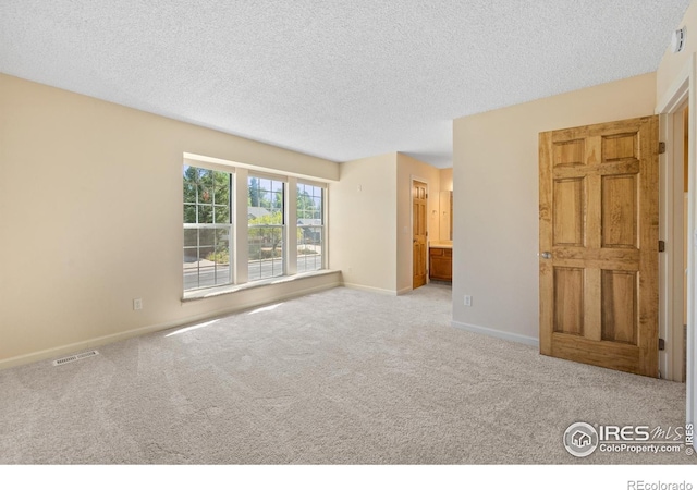 unfurnished room with light colored carpet and a textured ceiling