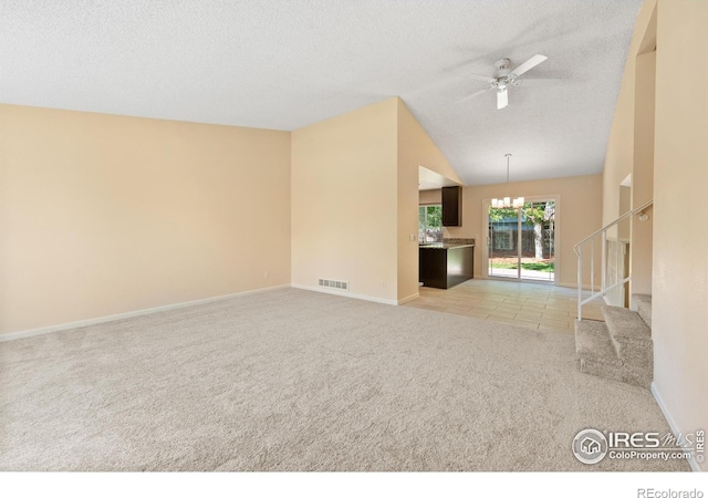 unfurnished living room featuring light carpet, lofted ceiling, a textured ceiling, and ceiling fan with notable chandelier