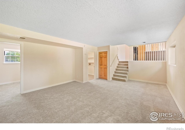 carpeted empty room featuring a textured ceiling