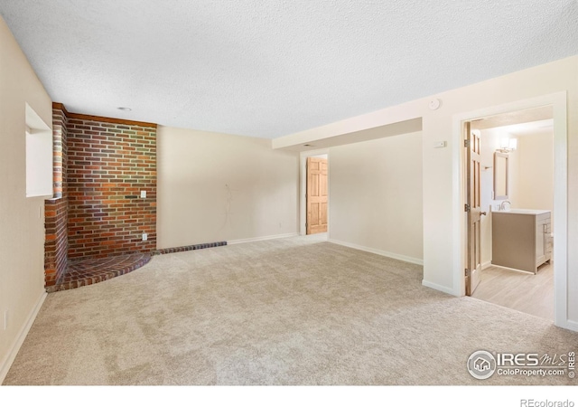 spare room featuring a textured ceiling and light carpet