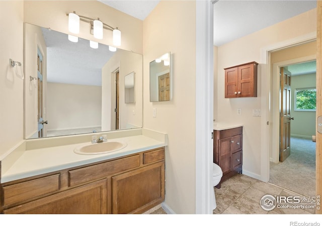 bathroom with a textured ceiling, vanity, toilet, and tile patterned floors