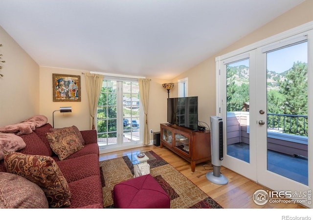 living room featuring hardwood / wood-style flooring, vaulted ceiling, and french doors