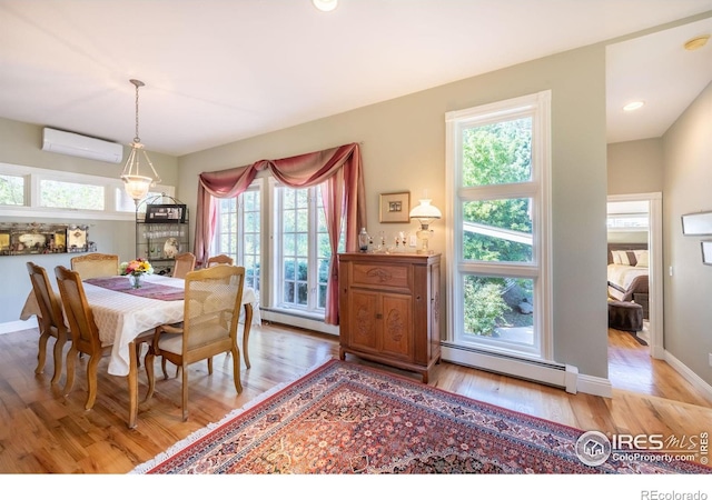 dining room featuring a baseboard heating unit, an AC wall unit, and light wood-type flooring