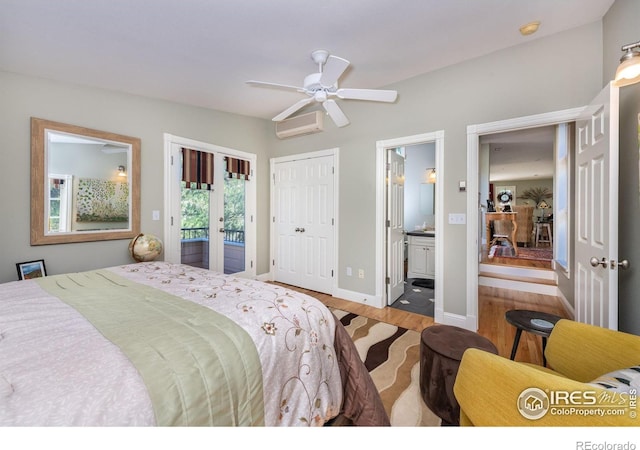 bedroom featuring french doors, ensuite bathroom, light hardwood / wood-style flooring, an AC wall unit, and access to outside