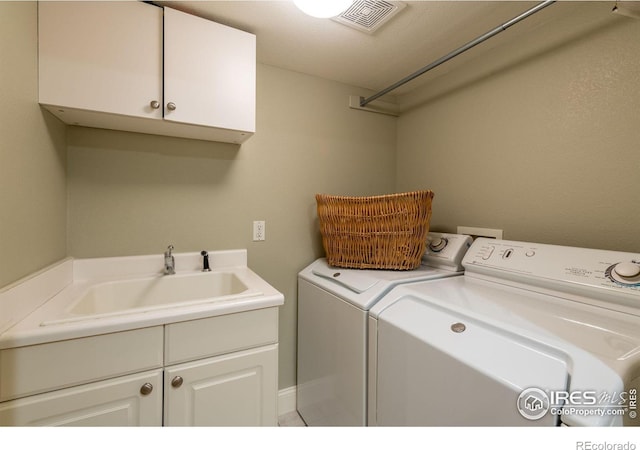 washroom with cabinets, washing machine and dryer, and sink