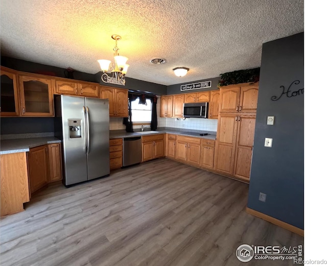 kitchen featuring sink, hanging light fixtures, a notable chandelier, light hardwood / wood-style floors, and stainless steel appliances