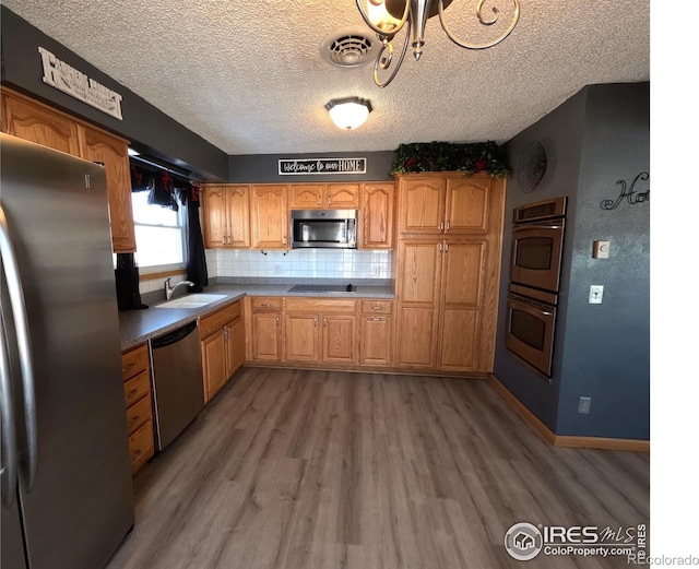 kitchen featuring sink, hardwood / wood-style floors, stainless steel appliances, tasteful backsplash, and a textured ceiling