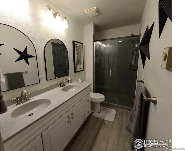 bathroom with hardwood / wood-style flooring, toilet, vanity, and a shower with shower door