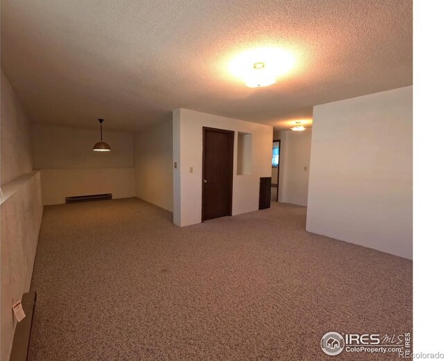 unfurnished room featuring a baseboard heating unit, carpet floors, and a textured ceiling