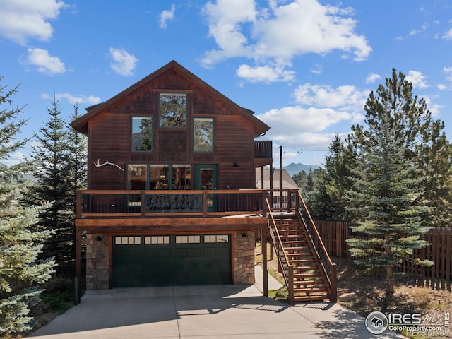 view of front of house featuring stairs, concrete driveway, stone siding, and a garage