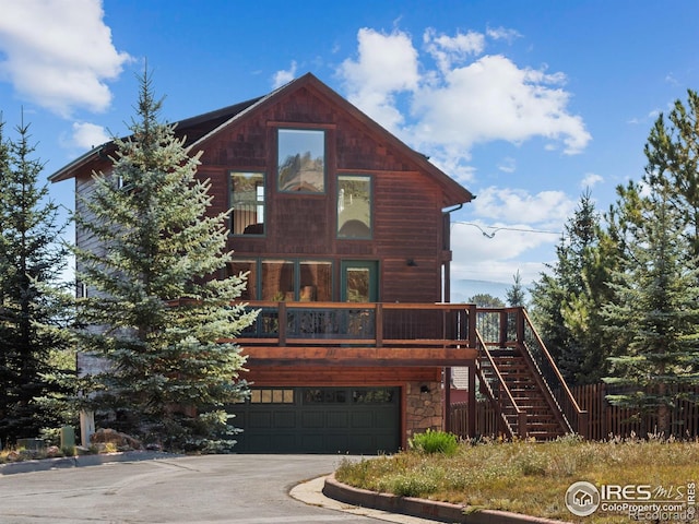 view of front of home with driveway, stone siding, an attached garage, and stairs