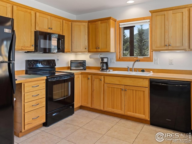 kitchen with black appliances, light tile patterned floors, light countertops, and a sink