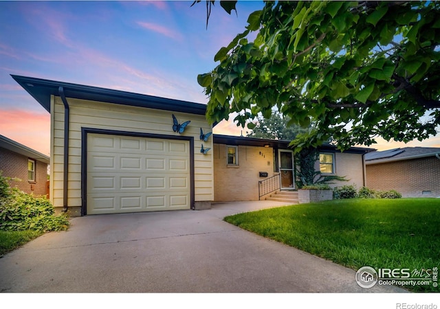 ranch-style home with a garage and a yard