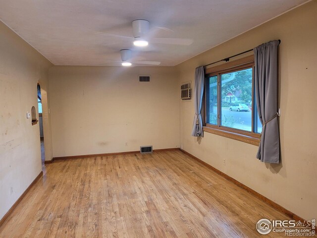 spare room featuring light hardwood / wood-style flooring, ceiling fan, and a wall mounted air conditioner