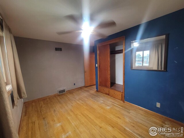 unfurnished bedroom with ceiling fan, a closet, and light wood-type flooring