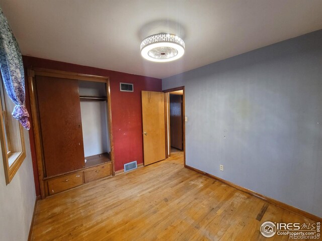 unfurnished bedroom featuring wood-type flooring and a closet