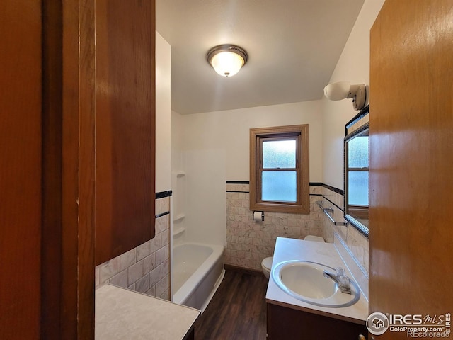 bathroom with a tub, vanity, tile walls, toilet, and hardwood / wood-style flooring