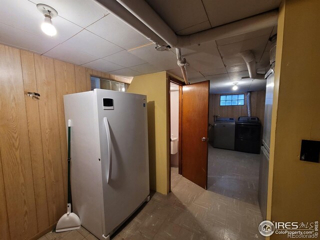 interior space with separate washer and dryer, wood walls, a paneled ceiling, and refrigerator