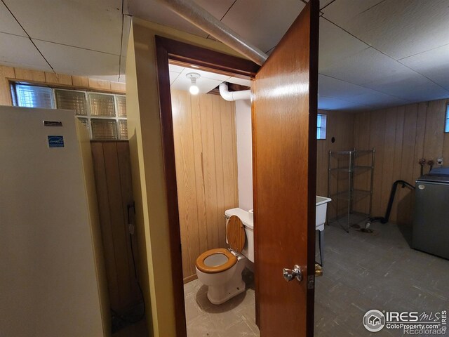 room details featuring white refrigerator and wood walls