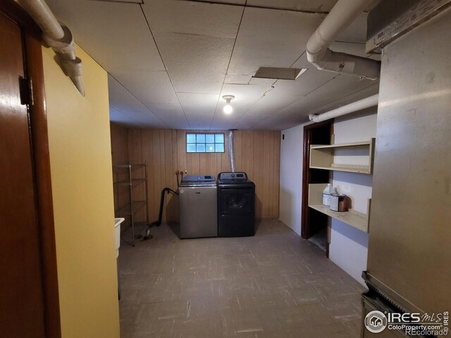 basement with wooden walls and washing machine and clothes dryer