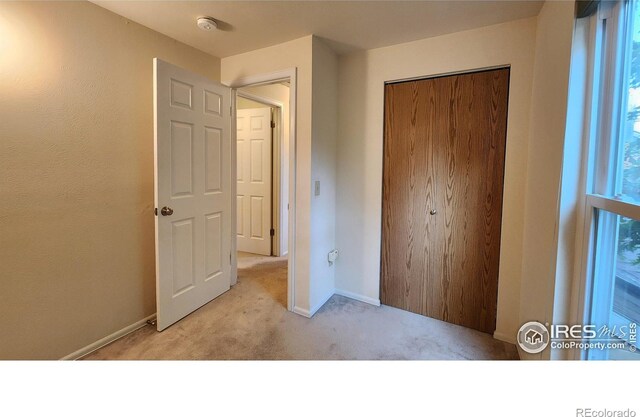 unfurnished bedroom with light carpet and a closet