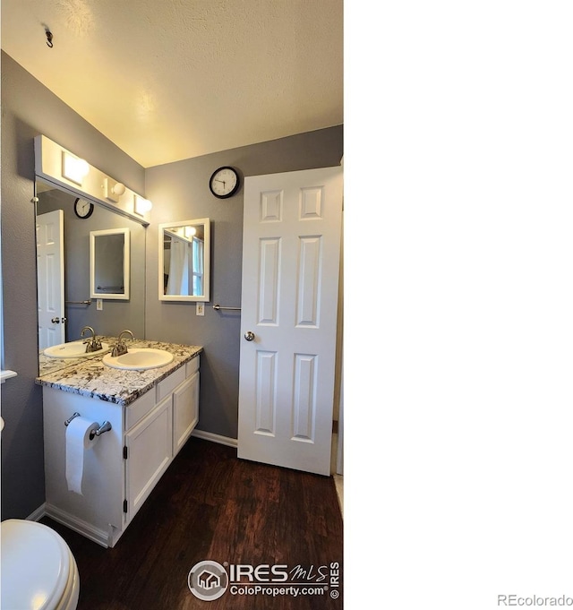 bathroom with hardwood / wood-style floors, vanity, and toilet