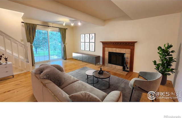 living room featuring a fireplace, light hardwood / wood-style floors, and beam ceiling