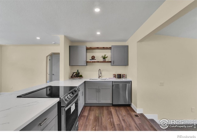 kitchen with dark hardwood / wood-style flooring, sink, light stone countertops, appliances with stainless steel finishes, and gray cabinetry