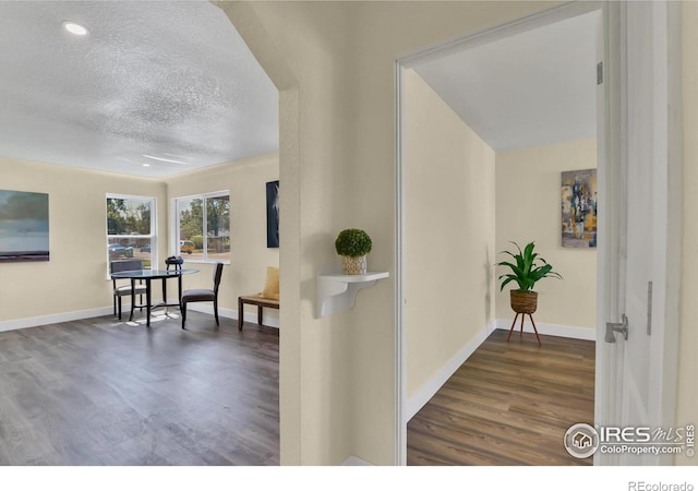 hallway featuring a textured ceiling and dark hardwood / wood-style floors