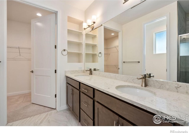 bathroom featuring an enclosed shower, a sink, a spacious closet, and double vanity