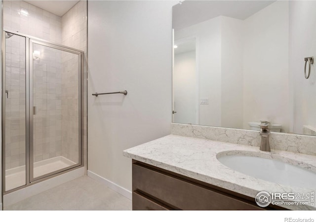 bathroom with a stall shower, tile patterned floors, vanity, and baseboards