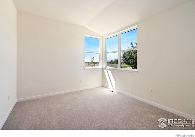 carpeted empty room with vaulted ceiling and baseboards