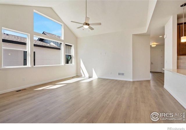 unfurnished room with light wood-style floors, visible vents, and high vaulted ceiling