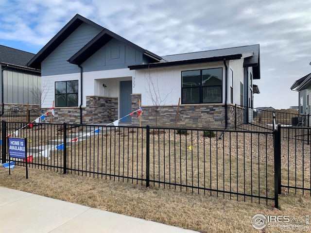 view of front of property with fence private yard and stone siding