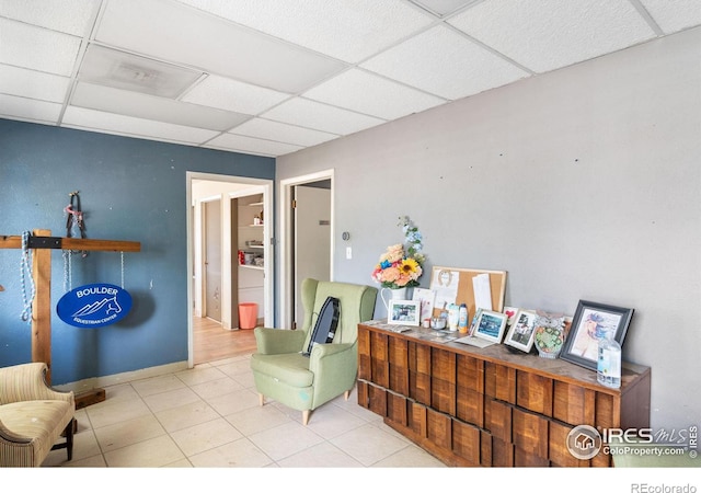 sitting room with light tile patterned floors and a paneled ceiling