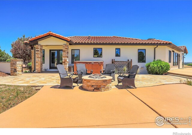 back of property with a patio area, a fire pit, and a hot tub