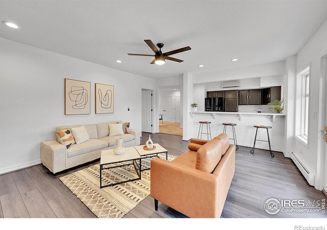 living room with ceiling fan, wood-type flooring, baseboard heating, and a wall mounted AC