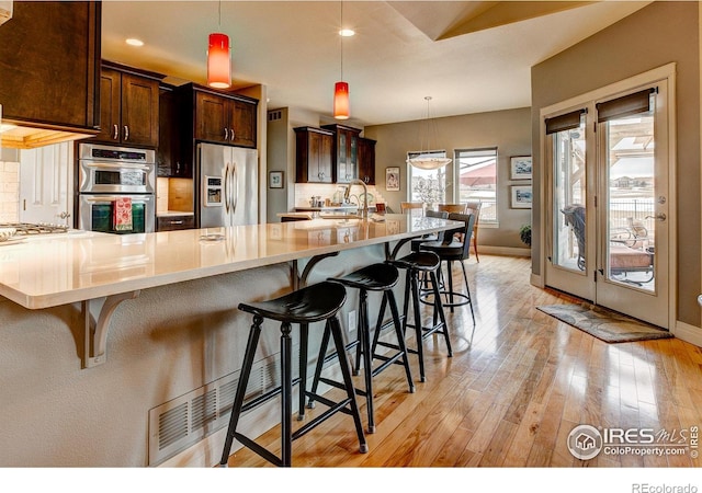 kitchen with plenty of natural light, stainless steel appliances, a kitchen breakfast bar, and hanging light fixtures