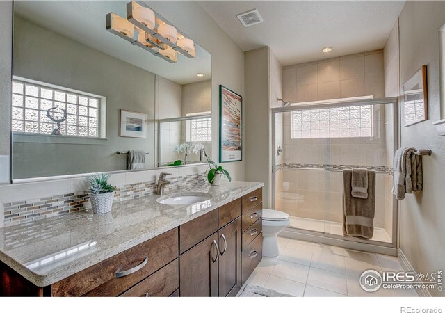 bathroom featuring vanity, toilet, walk in shower, and tile patterned floors