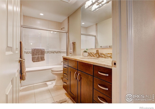 full bathroom with combined bath / shower with glass door, vanity, toilet, and tile patterned floors