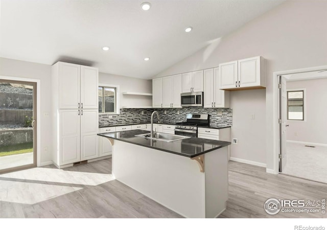 kitchen with lofted ceiling, appliances with stainless steel finishes, white cabinetry, and sink