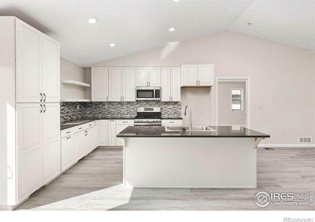 kitchen featuring stainless steel appliances, an island with sink, tasteful backsplash, white cabinets, and sink