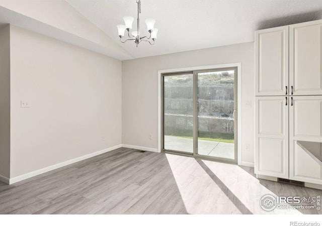 unfurnished dining area with light wood-type flooring, vaulted ceiling, and a chandelier