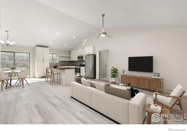 living room with lofted ceiling, light hardwood / wood-style floors, and ceiling fan with notable chandelier